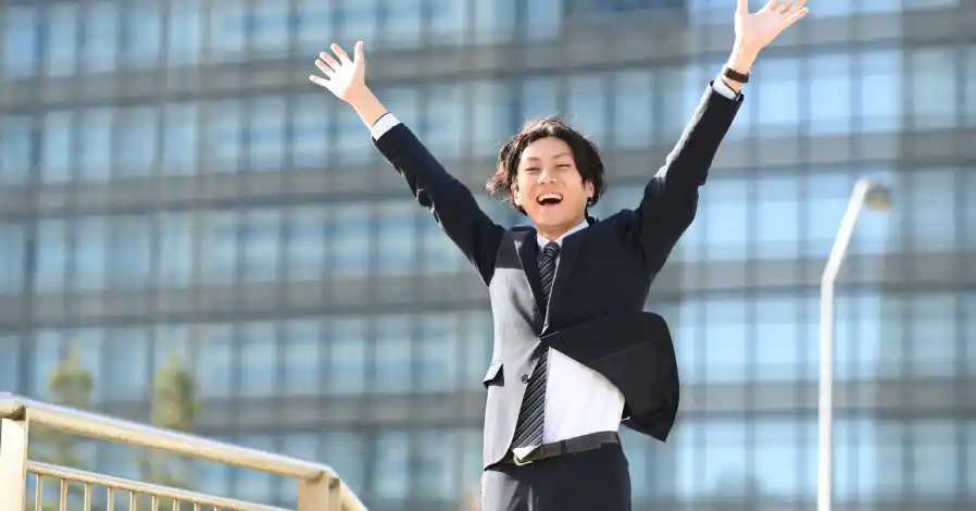 両手を上げて喜ぶスーツ姿の男性