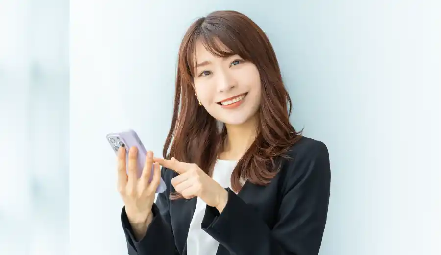 スマホを指さして微笑む女性