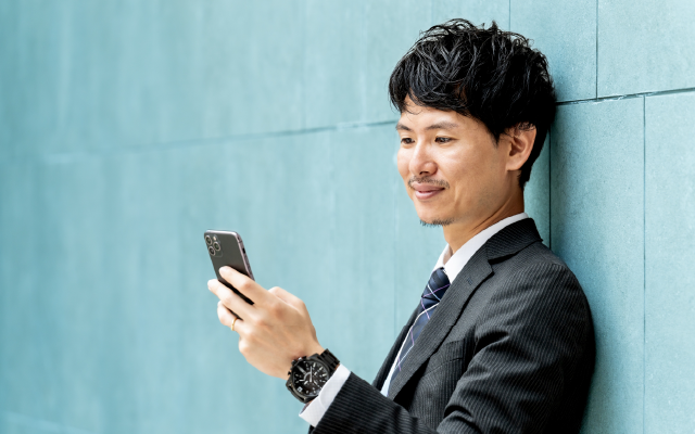 スマホを見て微笑むスーツの男性